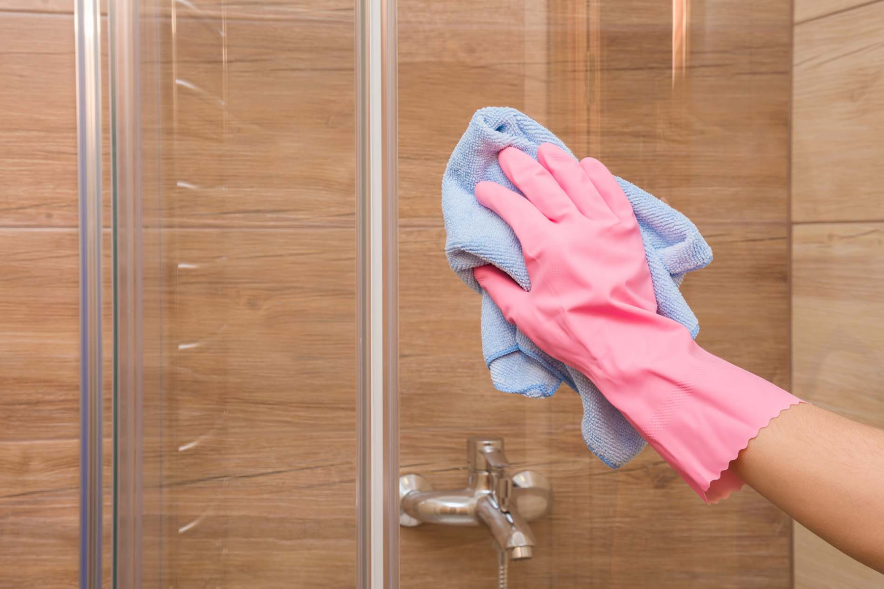 Homeowner Cleaning Shower Glass With Gloves And Microfibre Cloth