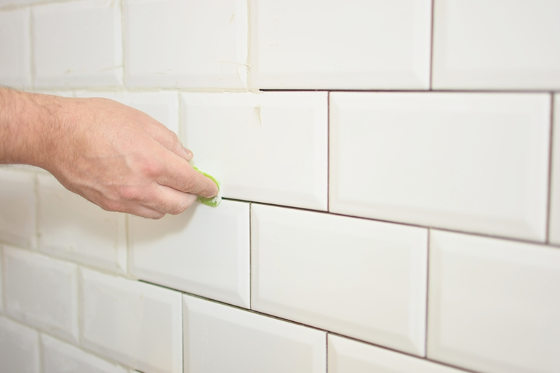Homeowner Grouting White Tiles In Bathroom