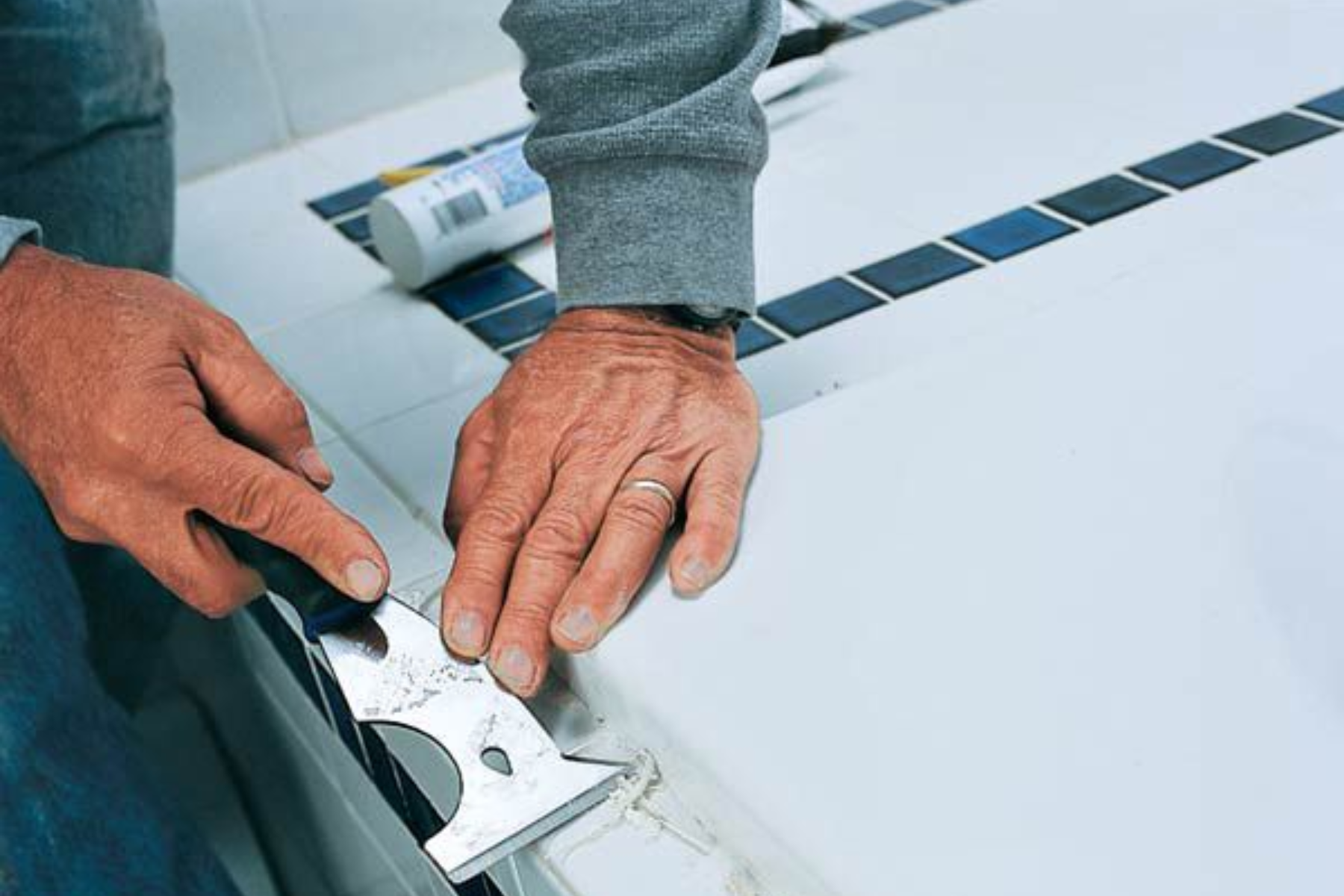 Homeowner Using Cutting Blades On Bathroom Sealant
