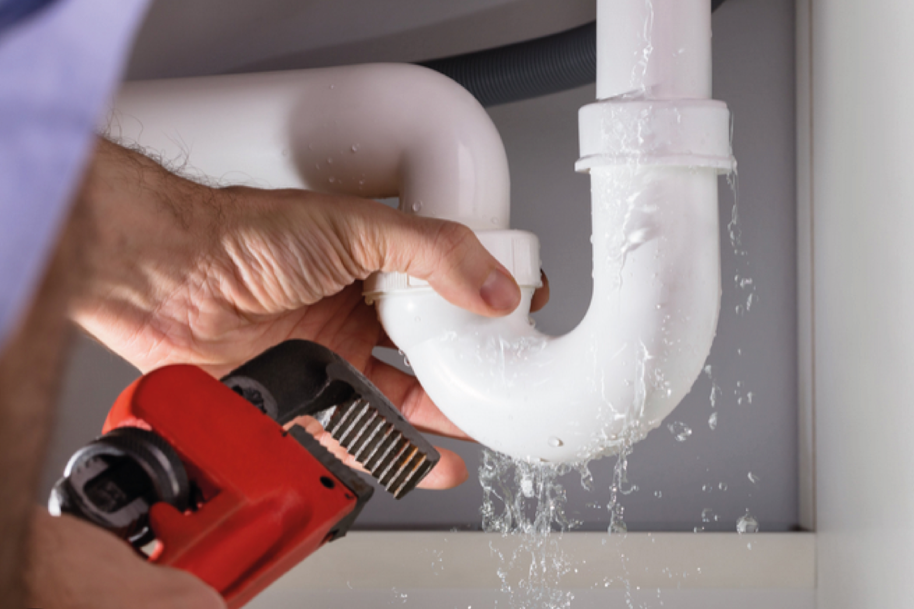 Plumber Fixing Plastic White Burst Pipe Under Sink