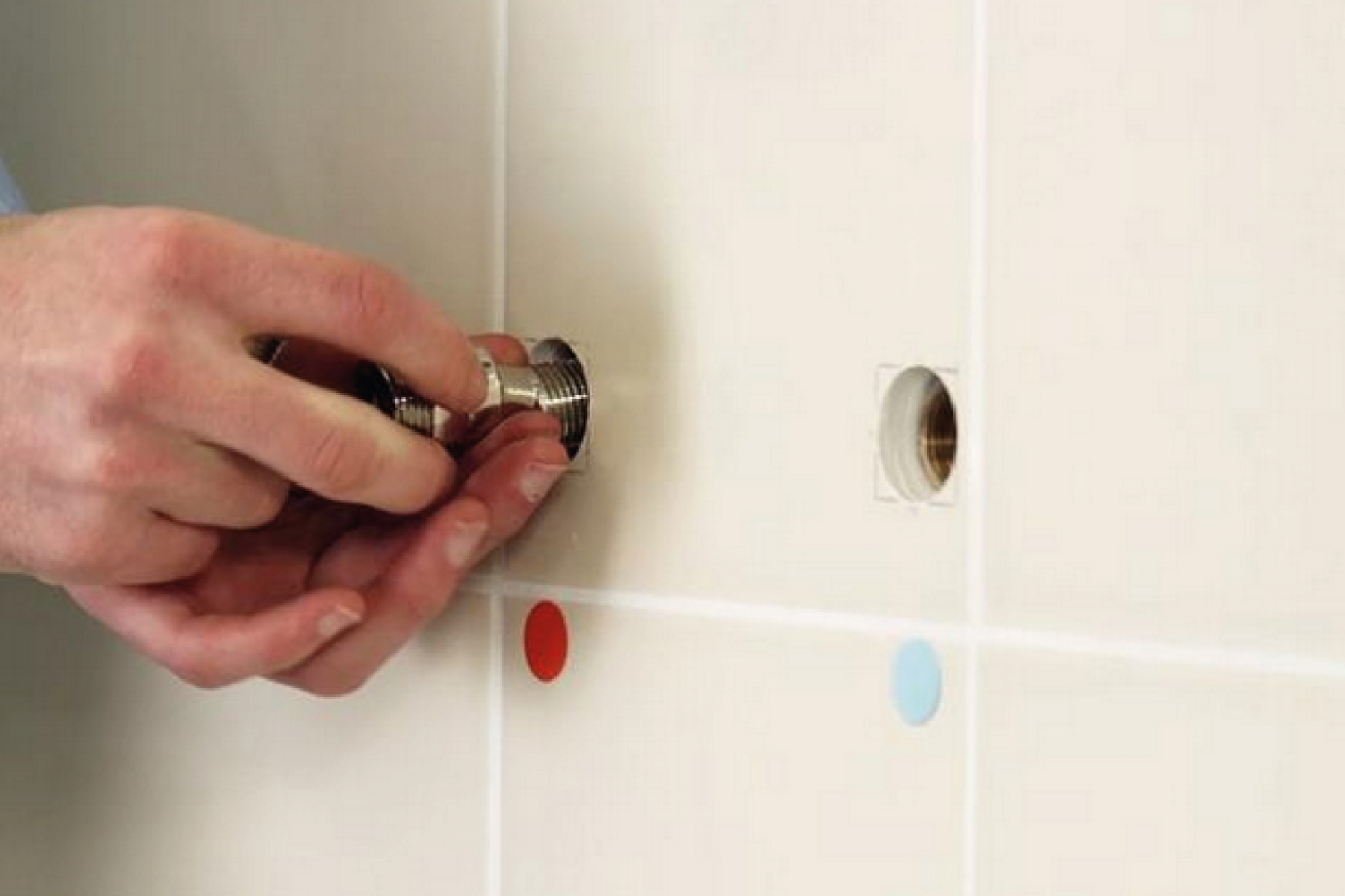 Plumber Inserting Valves Into Tiled Wall For Mixer Shower Installation 